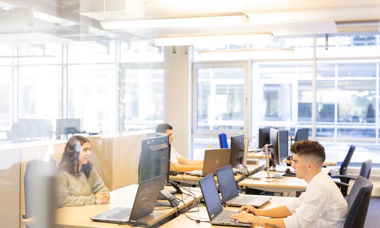 Mehrere Personen arbeiten an ihren Laptops in einem Coworking Space